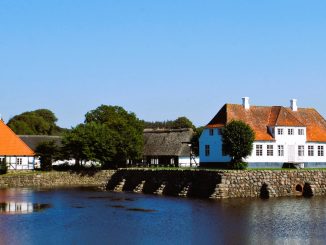 Herregården Søbygaard på Ærø med stråtag spejlet i voldgraven