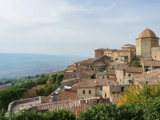 Den middelalderlige bydel i Volterra med tegltage og klokketårn over det toscanske landskab