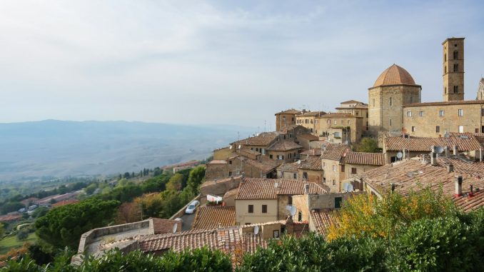 Den middelalderlige bydel i Volterra med tegltage og klokketårn over det toscanske landskab